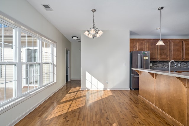 kitchen featuring a chandelier, decorative backsplash, hanging light fixtures, high end fridge, and a healthy amount of sunlight