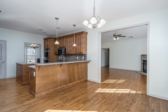 kitchen featuring a breakfast bar area, decorative backsplash, hardwood / wood-style flooring, kitchen peninsula, and stainless steel appliances