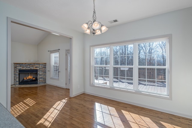 unfurnished living room with an inviting chandelier, hardwood / wood-style floors, and a healthy amount of sunlight