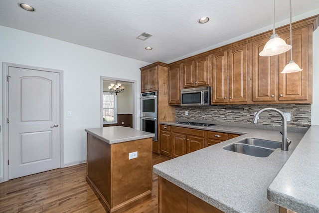 kitchen featuring appliances with stainless steel finishes, pendant lighting, sink, a center island, and a notable chandelier