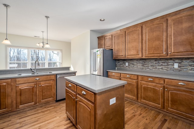 kitchen with sink, tasteful backsplash, decorative light fixtures, appliances with stainless steel finishes, and a kitchen island