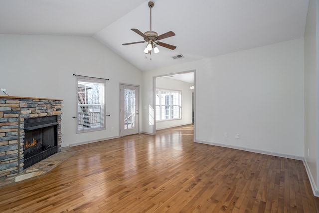 unfurnished living room with a stone fireplace, vaulted ceiling, ceiling fan, and hardwood / wood-style flooring