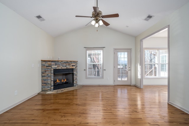 unfurnished living room with lofted ceiling, a stone fireplace, wood-type flooring, and ceiling fan