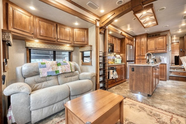 kitchen with sink, refrigerator, an island with sink, decorative backsplash, and oven