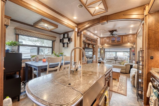 kitchen featuring decorative columns, ornamental molding, a center island, and a wealth of natural light