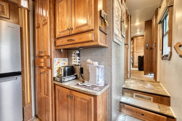 kitchen featuring stainless steel fridge and light stone countertops