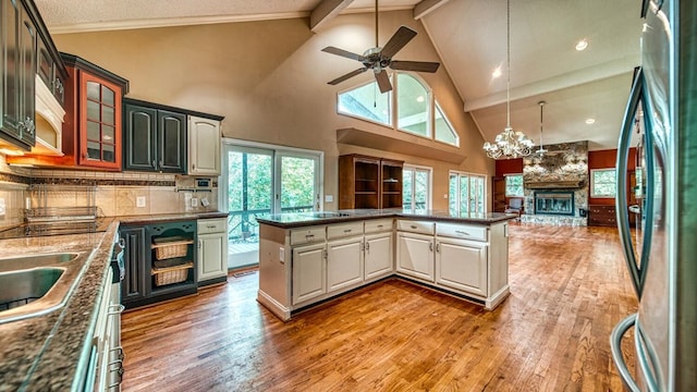 kitchen with dark countertops, backsplash, light wood-style floors, open floor plan, and stainless steel fridge