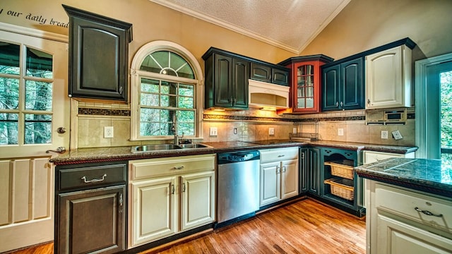 kitchen featuring a sink, vaulted ceiling, ornamental molding, stainless steel dishwasher, and light wood finished floors