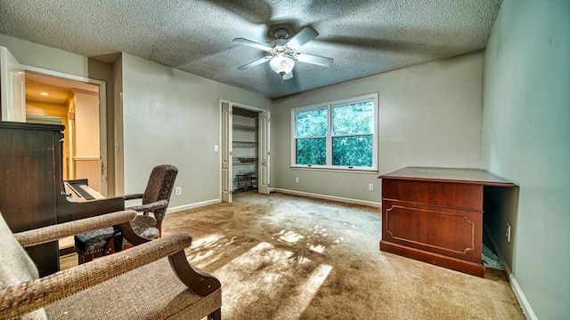 carpeted office space featuring a ceiling fan, a textured ceiling, and baseboards