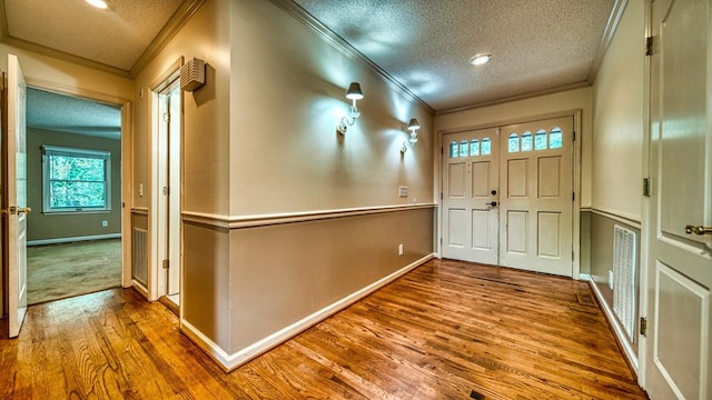 foyer with baseboards, ornamental molding, a textured ceiling, and wood finished floors