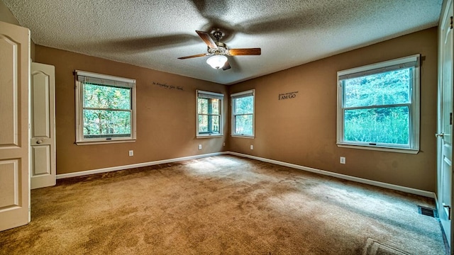 unfurnished room with ceiling fan, a textured ceiling, carpet floors, visible vents, and baseboards