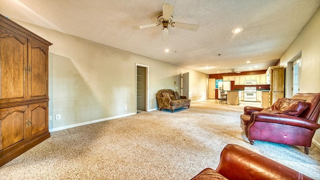 living room featuring ceiling fan, a textured ceiling, recessed lighting, light carpet, and baseboards