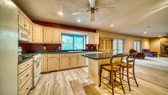 kitchen featuring dark countertops, white appliances, a sink, and a kitchen bar