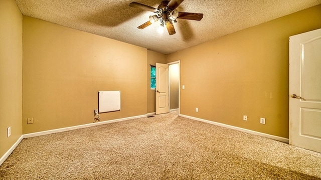 spare room with a textured ceiling, ceiling fan, carpet, and baseboards