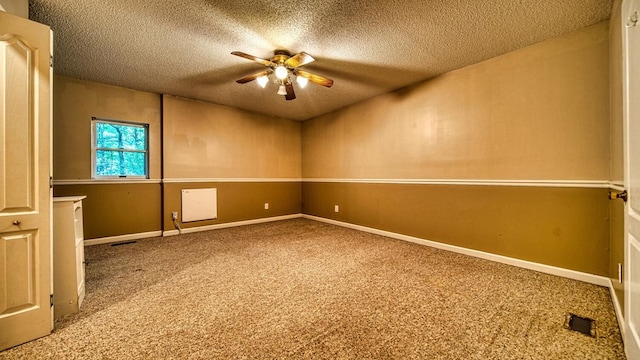 carpeted spare room featuring ceiling fan, visible vents, baseboards, and a textured ceiling