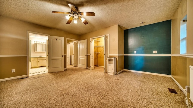 unfurnished bedroom with carpet flooring, ensuite bath, a textured ceiling, and baseboards