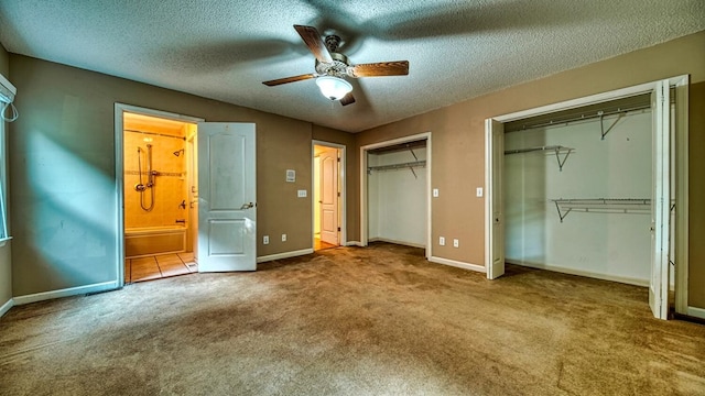 unfurnished bedroom featuring carpet, multiple closets, a ceiling fan, a textured ceiling, and baseboards