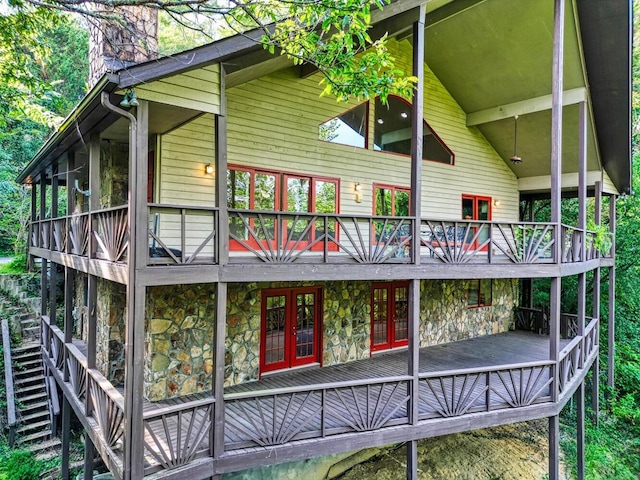 view of home's exterior featuring stone siding, a chimney, french doors, and a deck