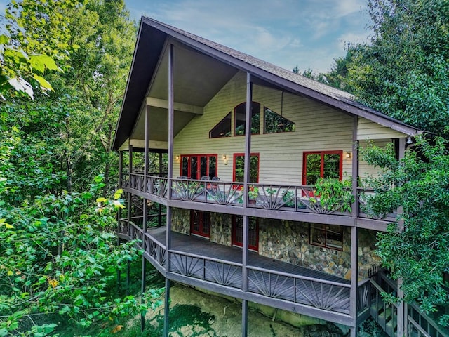 back of property featuring stone siding, a wooden deck, and french doors