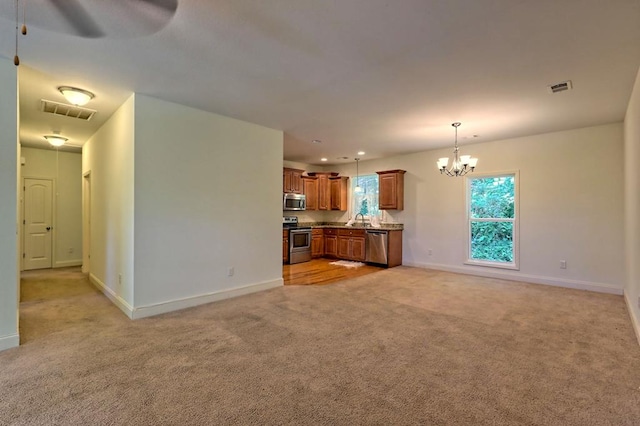 unfurnished living room with ceiling fan with notable chandelier, light colored carpet, and sink