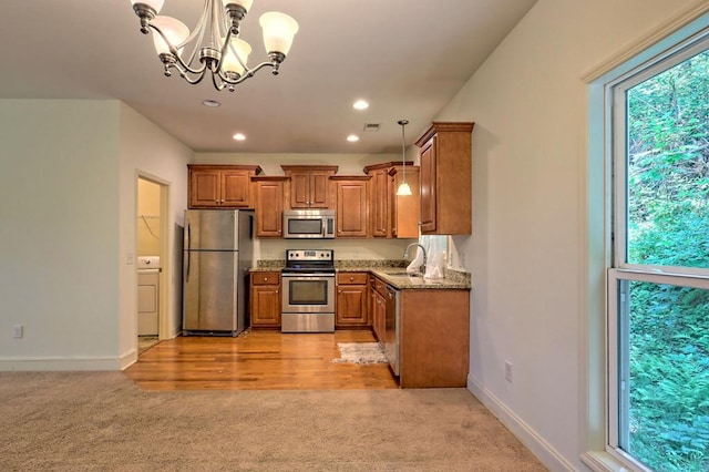 kitchen featuring light carpet, light stone countertops, stainless steel appliances, decorative light fixtures, and an inviting chandelier