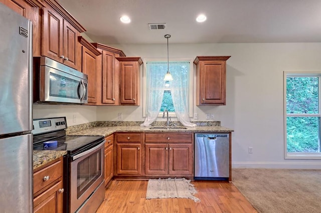 kitchen featuring a wealth of natural light, sink, stainless steel appliances, and light hardwood / wood-style flooring