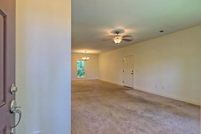 spare room with light carpet and ceiling fan with notable chandelier