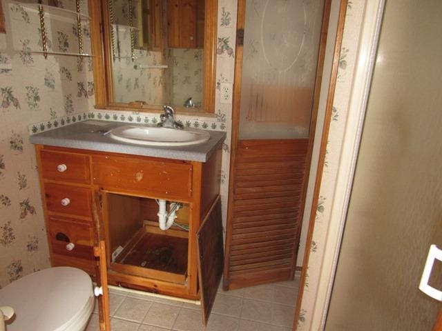 bathroom with toilet, vanity, and tile patterned floors