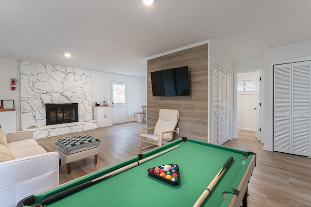 rec room featuring a stone fireplace, crown molding, a healthy amount of sunlight, and billiards