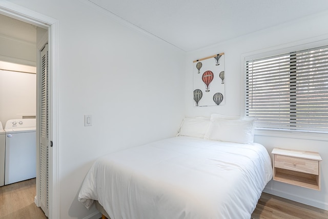 bedroom featuring washing machine and dryer, light hardwood / wood-style flooring, a closet, and crown molding