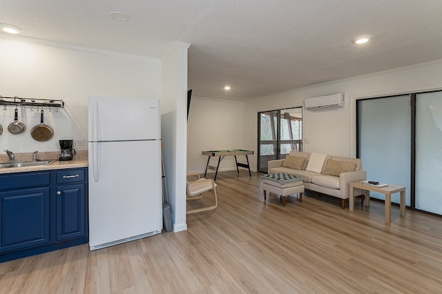 kitchen with a wall mounted air conditioner, sink, light hardwood / wood-style flooring, a textured ceiling, and white fridge