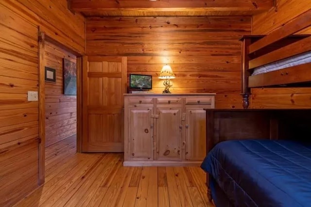 unfurnished bedroom with light hardwood / wood-style floors and wood walls