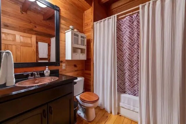 bathroom with vanity, toilet, hardwood / wood-style flooring, and wooden walls