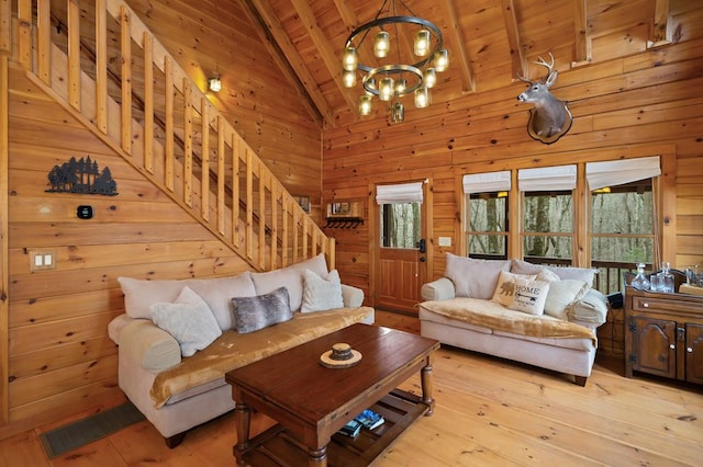 living room featuring stairs, wood walls, wooden ceiling, beamed ceiling, and light wood-type flooring