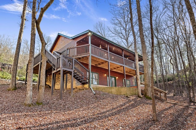 back of house featuring stairs, a deck, log veneer siding, and a ceiling fan