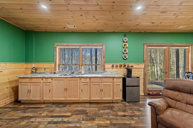 kitchen with wainscoting, wooden ceiling, freestanding refrigerator, light brown cabinets, and a sink