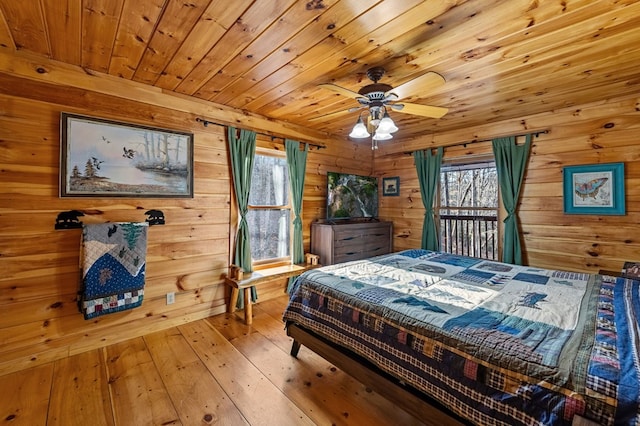 bedroom with wood walls, multiple windows, wooden ceiling, and light wood-style floors