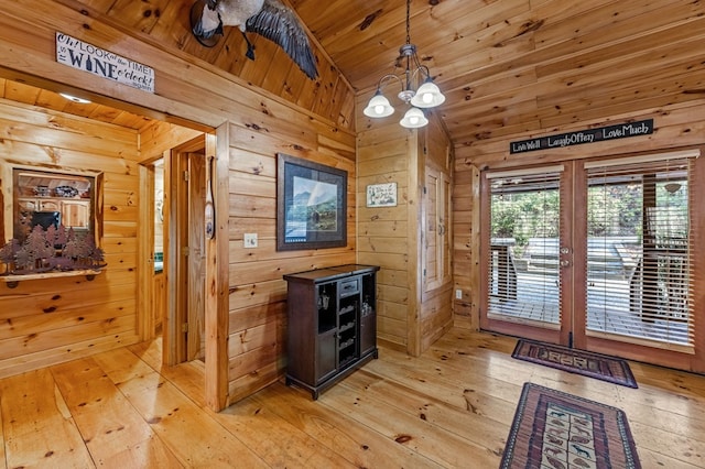 doorway to outside with light wood finished floors, an inviting chandelier, wood ceiling, vaulted ceiling, and wood walls