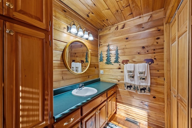 bathroom with wood ceiling, visible vents, vanity, and wooden walls