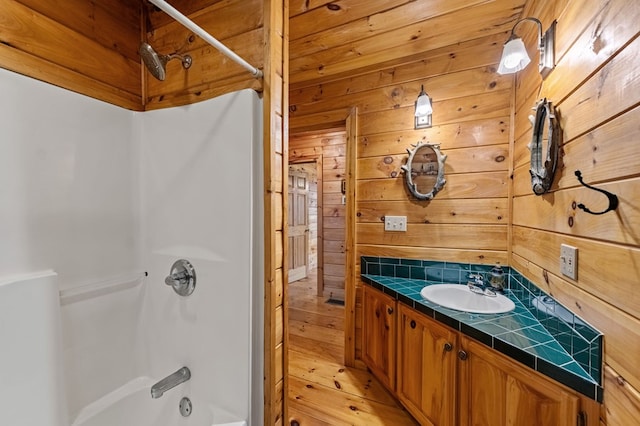 full bath with wood walls, shower / washtub combination, and vanity