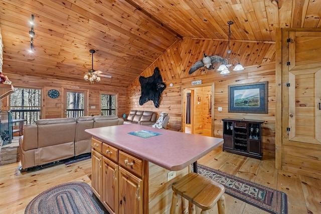 kitchen with open floor plan, a kitchen island, wooden walls, light wood-type flooring, and a kitchen breakfast bar