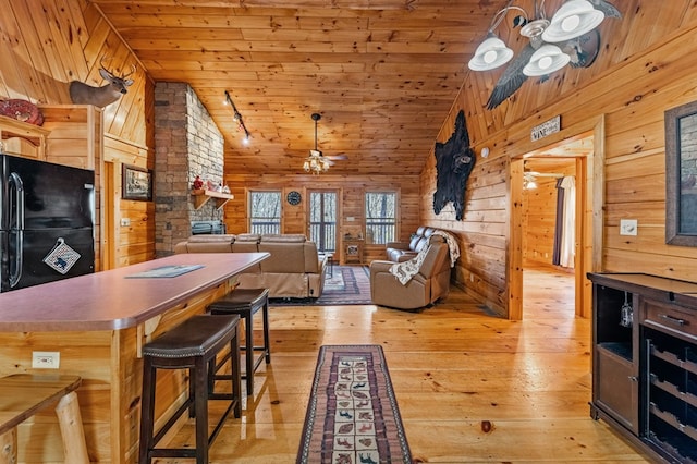 interior space featuring ceiling fan, wooden ceiling, wood walls, vaulted ceiling, and light wood-type flooring