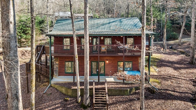 rear view of house with metal roof, a patio, a deck, and stairs