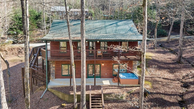 back of house featuring a deck, a patio, metal roof, a jacuzzi, and stairs