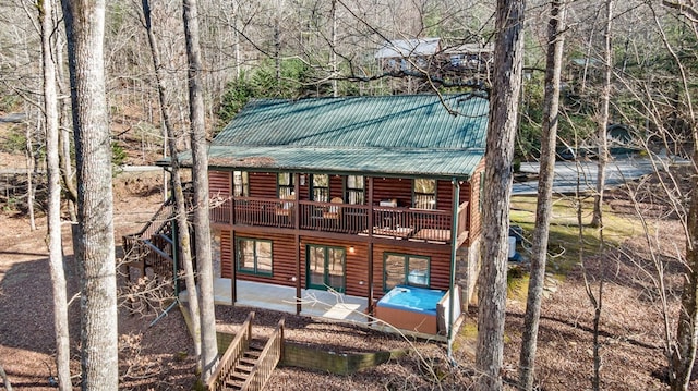 rear view of property featuring faux log siding, a patio, a deck, and metal roof