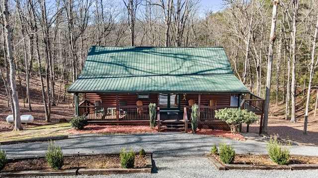 view of front of house featuring a porch, metal roof, and driveway