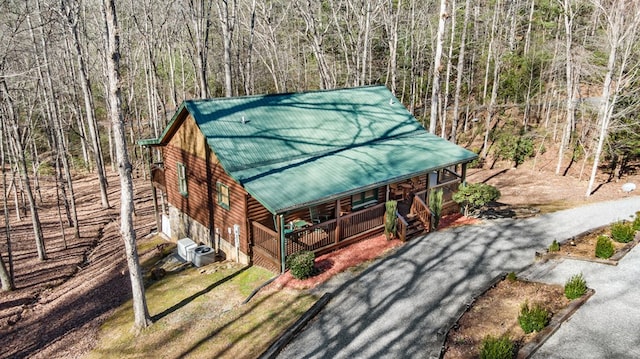 view of front of house with covered porch, metal roof, driveway, and a view of trees