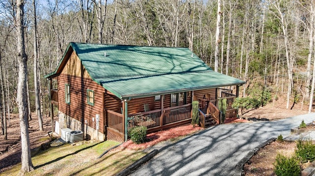 view of front of property featuring aphalt driveway, cooling unit, covered porch, and metal roof