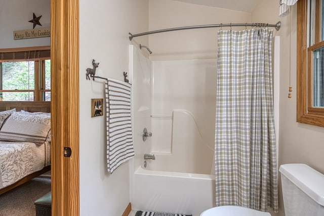 ensuite bathroom featuring toilet, shower / bath combo with shower curtain, and lofted ceiling