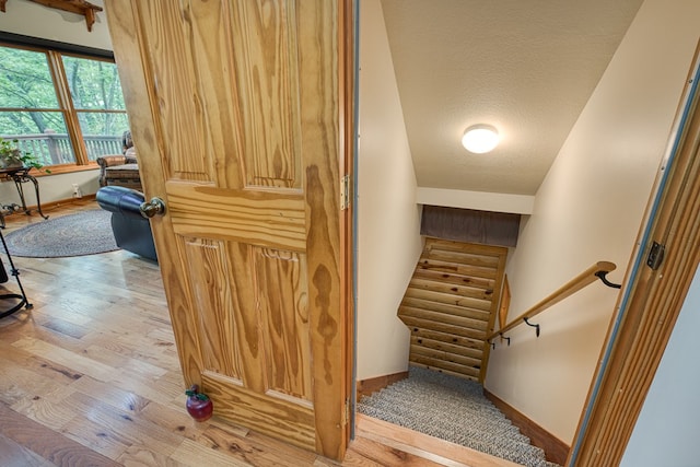 stairs with hardwood / wood-style flooring, a textured ceiling, and baseboards